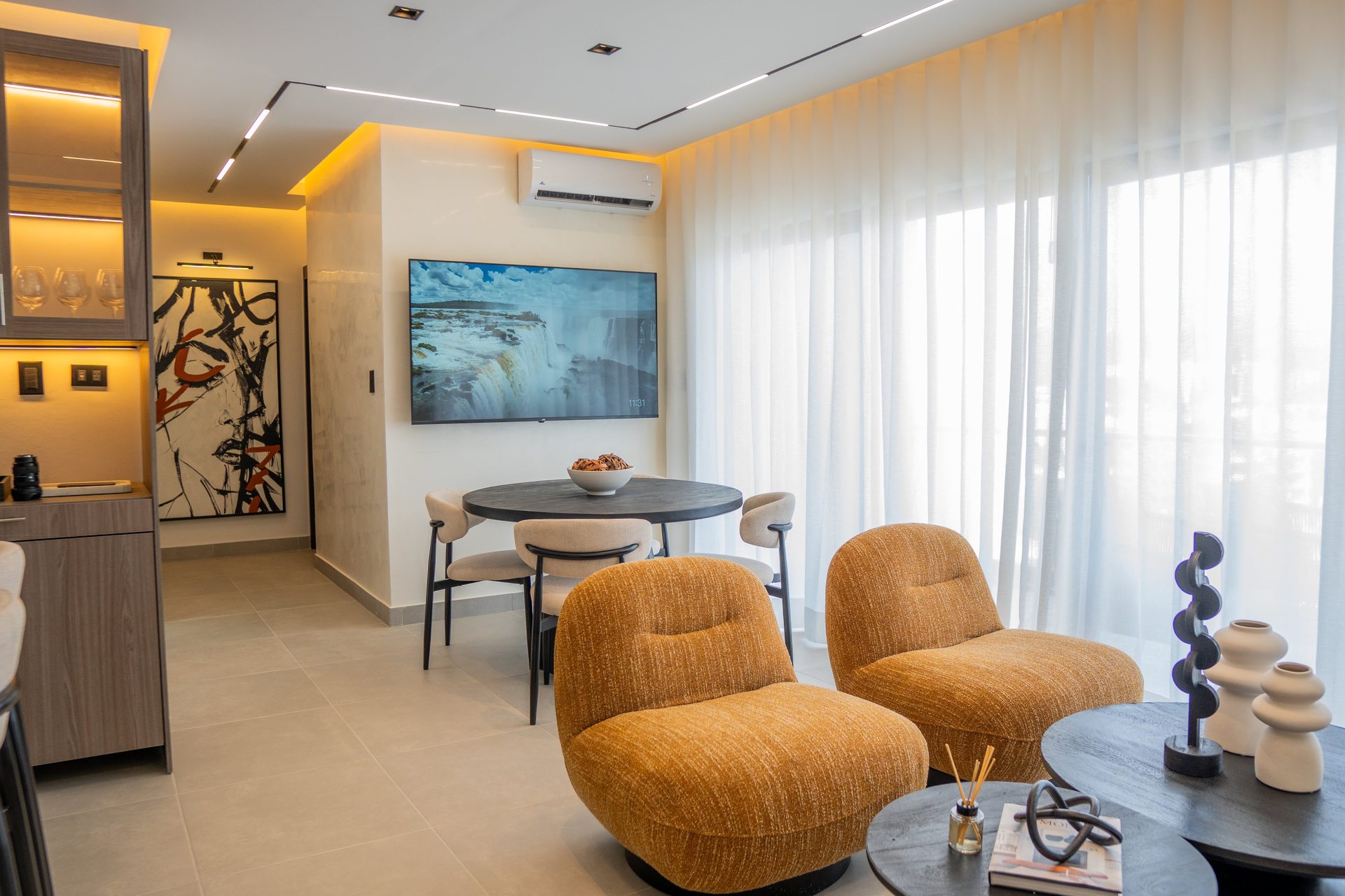 Sala de estar con butacas de acento en coral y obra de arte por A. Guzman Studio