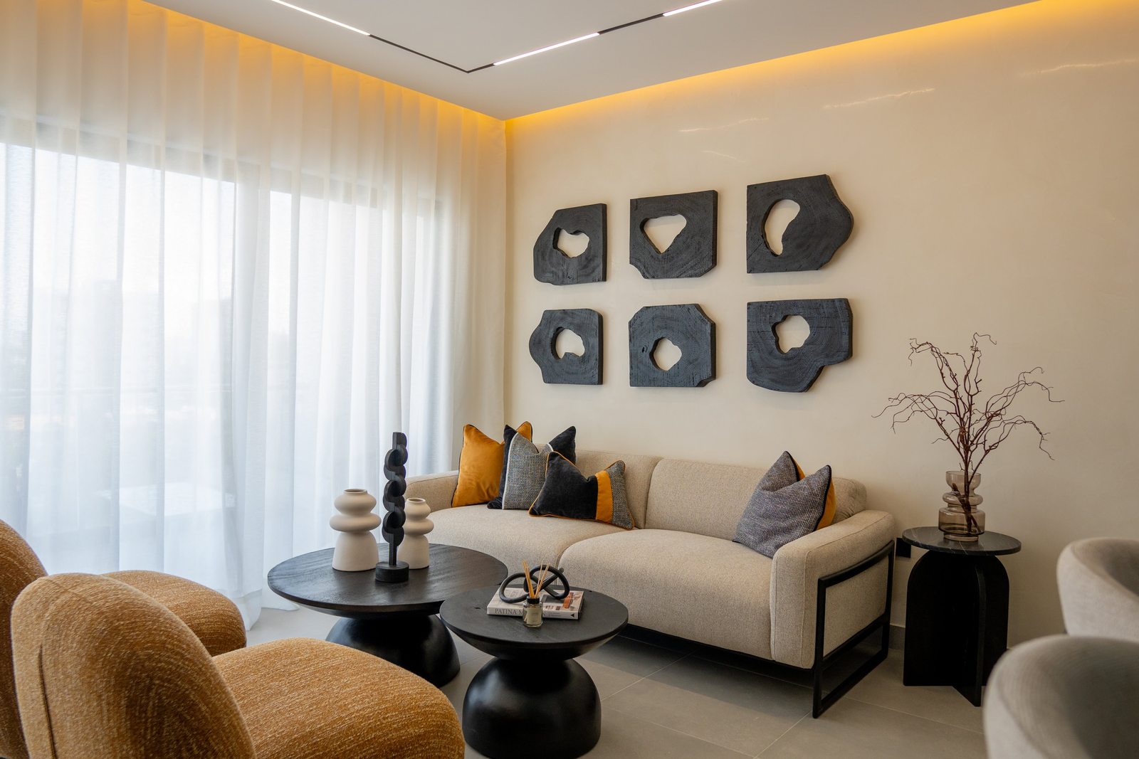Sala con pared de espejos circulares, sofá y vegetación por A. Guzman Studio