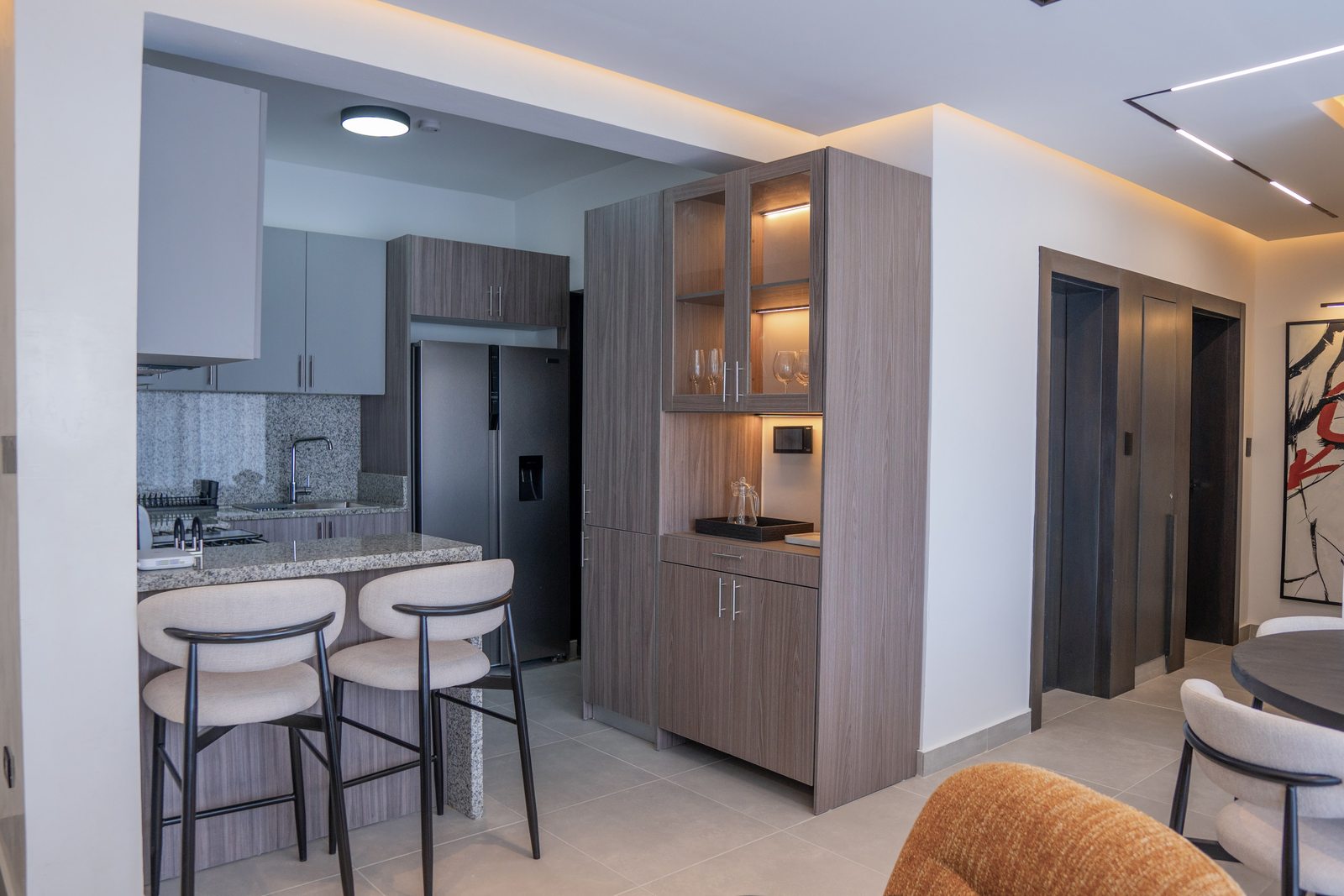Cocina con barra e isla y banquetas por A. Guzman Studio
