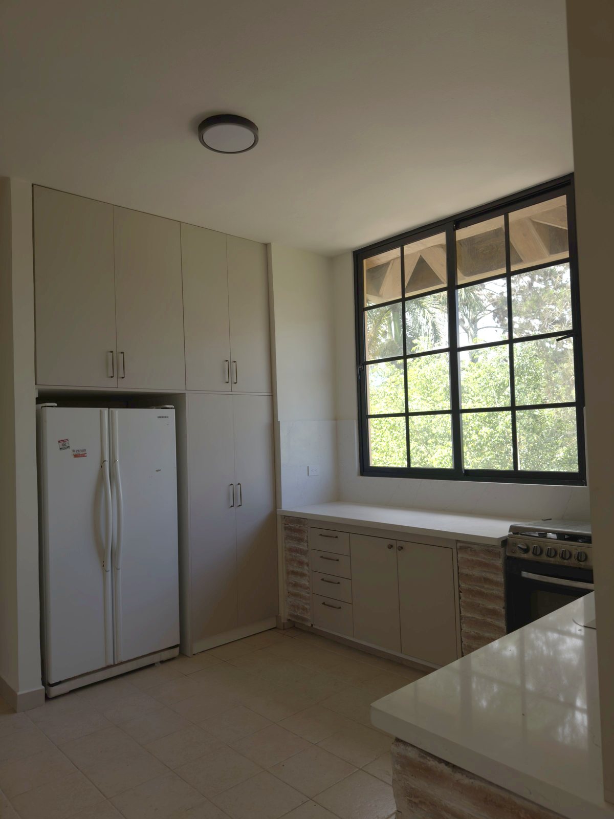 Cocina con ventana hacia el jardín y luz natural por A. Guzman Studio