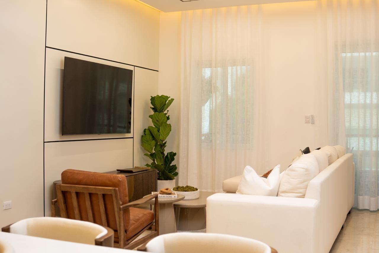 Sala con sofás neutros y división de vidrio por A. Guzman Studio