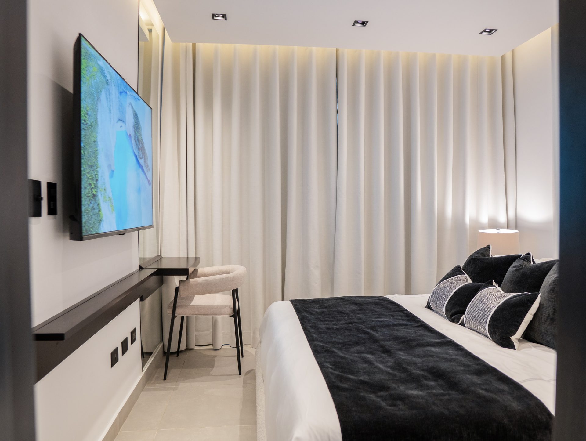 Dormitorio con pared multimedia en madera, cama y alfombra azul por A. Guzman Studio