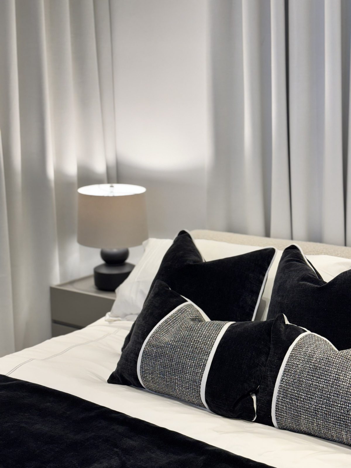 Dormitorio con cabecero y cojines en gris por A. Guzman Studio
